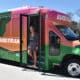 “Contest winner Kaitlin Barninger stands aboard the Laketran bus wrapped in her design.” PHOTO CREDIT: Images © 2023 Avery Dennison Corporation
